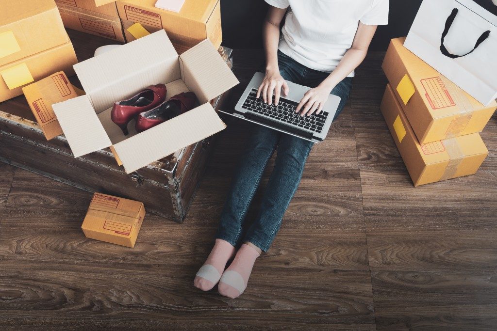 online store owner with a laptop surrounded by shipment boxes