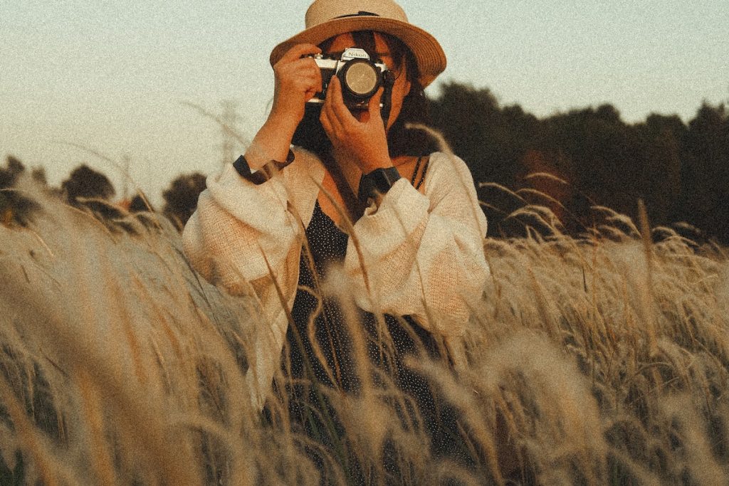 unrecognizable female photographer taking photo on camera in field