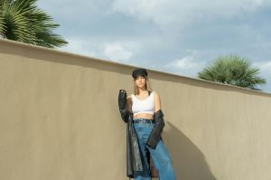 woman wearing a white crop top, a black belt, a black beret, and baggy jeans